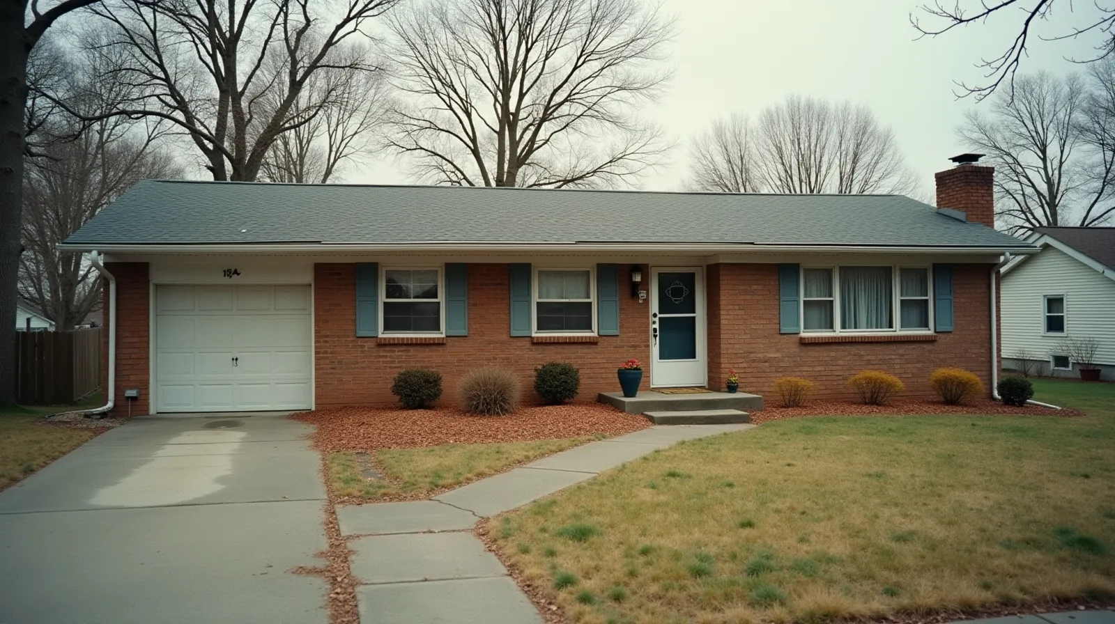 Empty single-story brick ranch house with overgrown lawn, vacant and awaiting estate sale