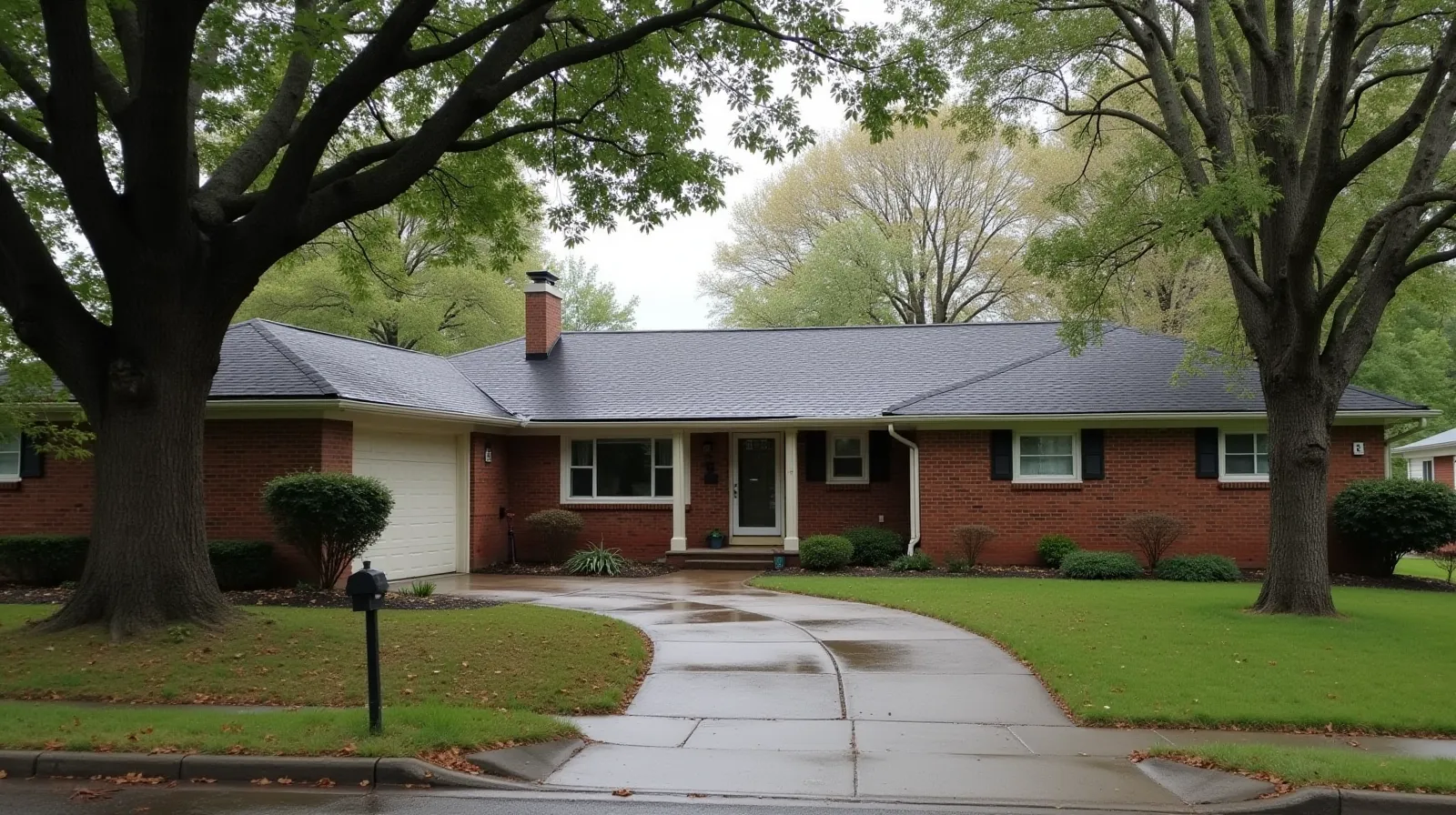 Suburban brick ranch house with section of missing asphalt shingles exposing roof decking, overcast sky, oak trees in background