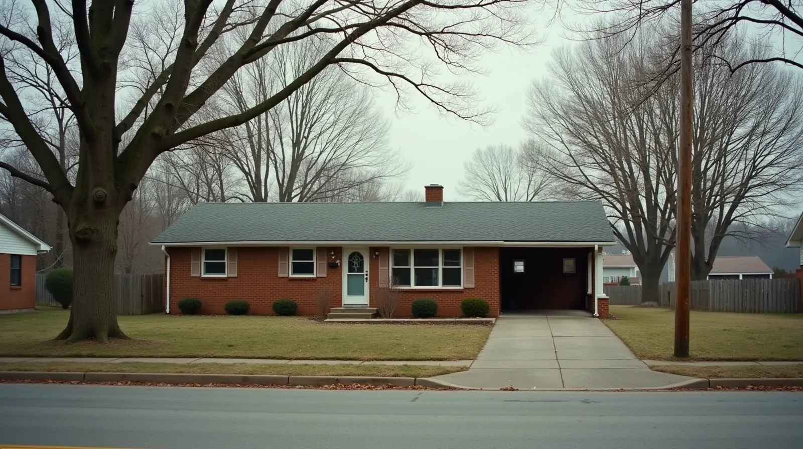 Single-story 1960s brick ranch house with a carport on a quiet Gallatin, Tennessee street on an overcast morning