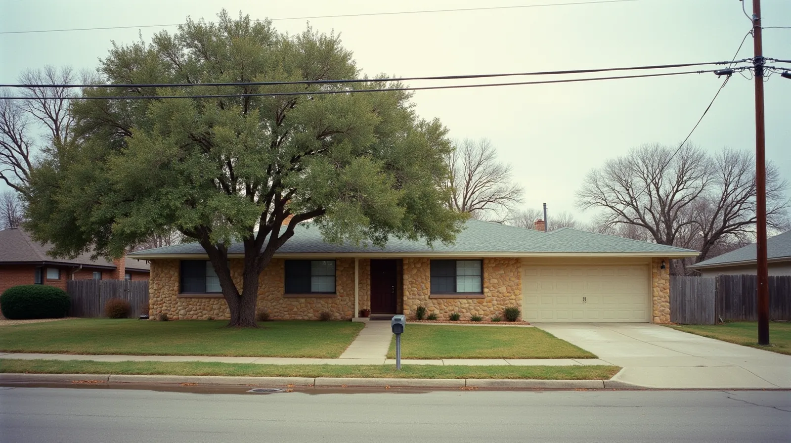 1960s stone ranch house in New Braunfels Texas with live oak tree and Hill Country limestone
