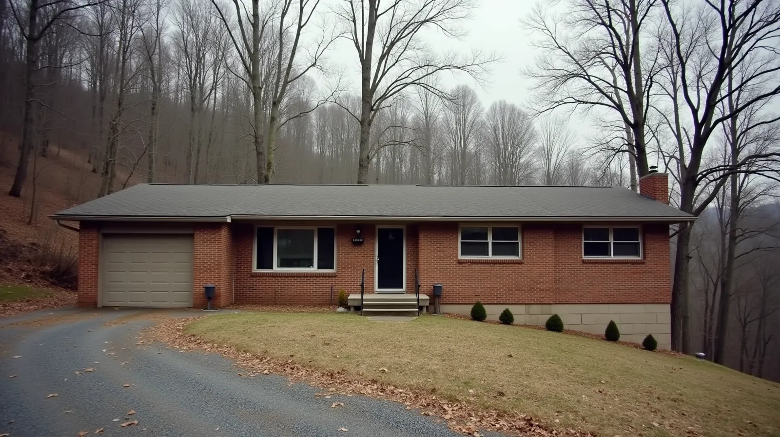 Brick ranch house with concrete block foundation in wooded eastern Tennessee hillside, overcast sky