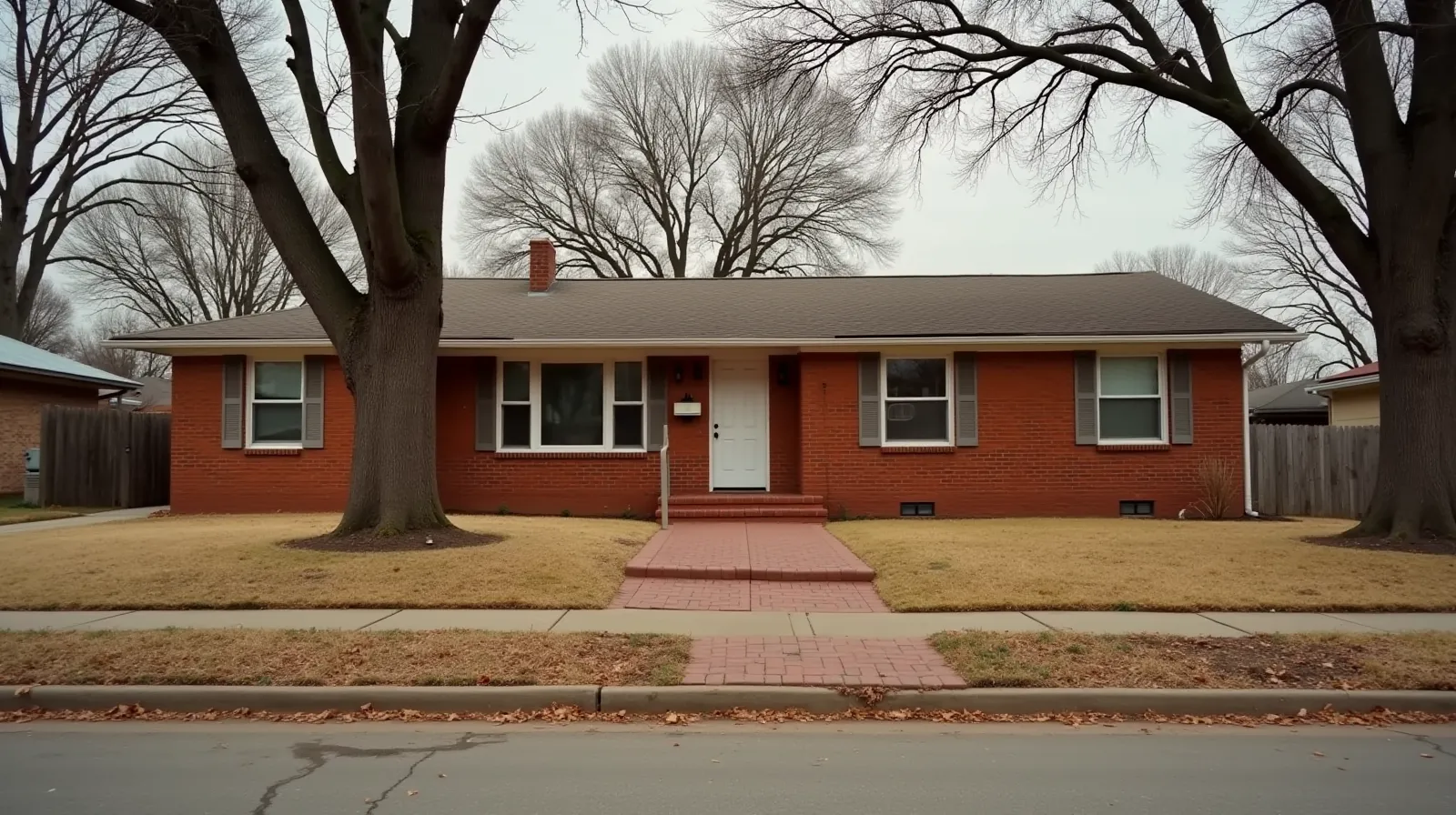 1960s brick ranch house on a North Tulsa residential street with red clay soil and post oak trees